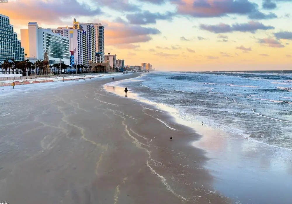 Playa al atardecer con paseo marítimo y hoteles frente al mar