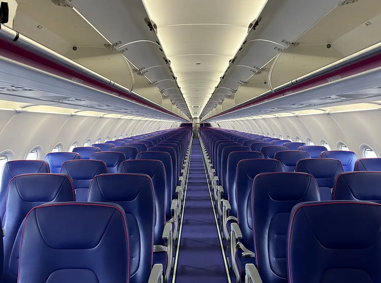 Cabina interior de un avión de Wizz Air con sus asientos morados
