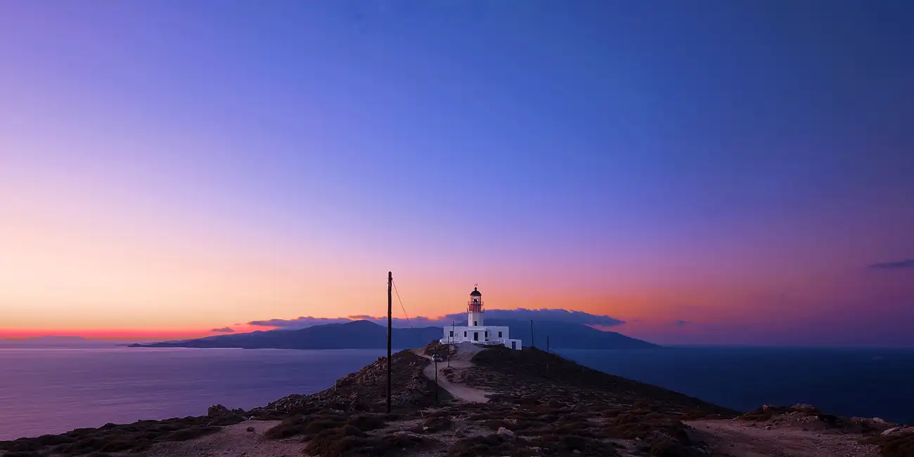 Faro de Armenistis en el cabo noroeste de Mykonos al atardecer, con la isla de Tinos al fondo