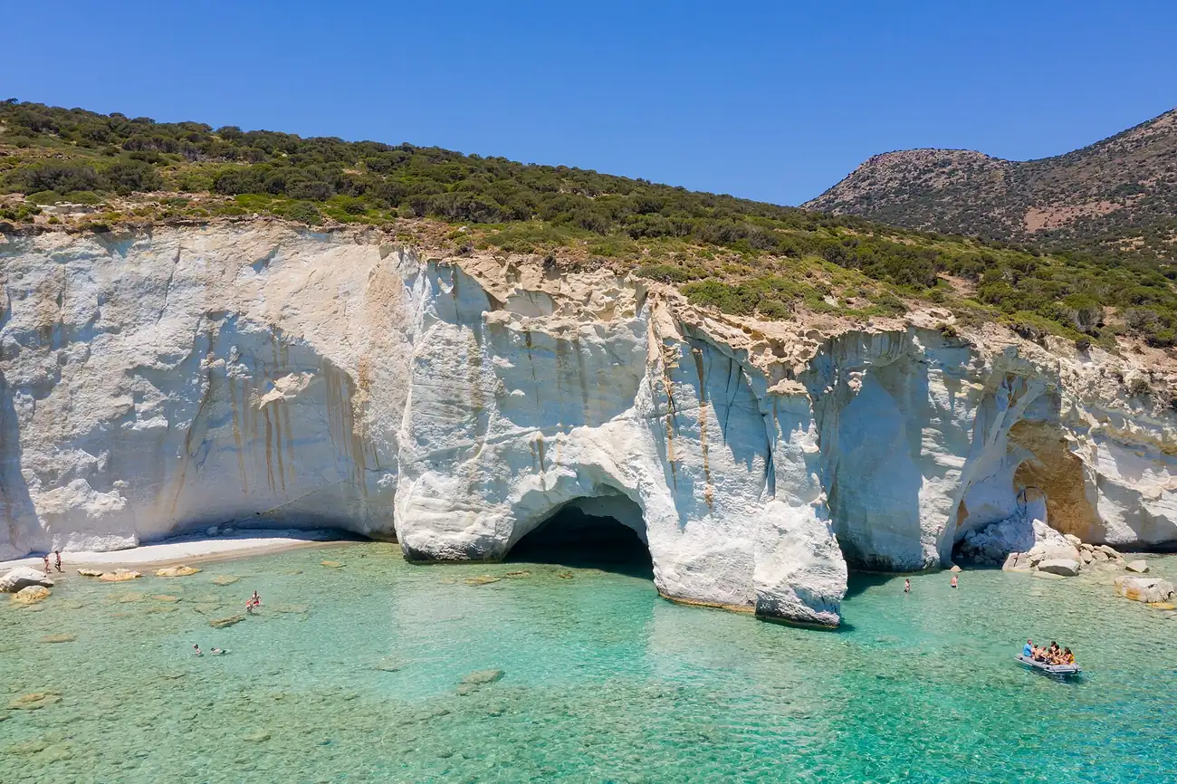 Arcos y cuevas en la roca blanca de Kleftiko, en la costa sur de Milos, con una lancha delante