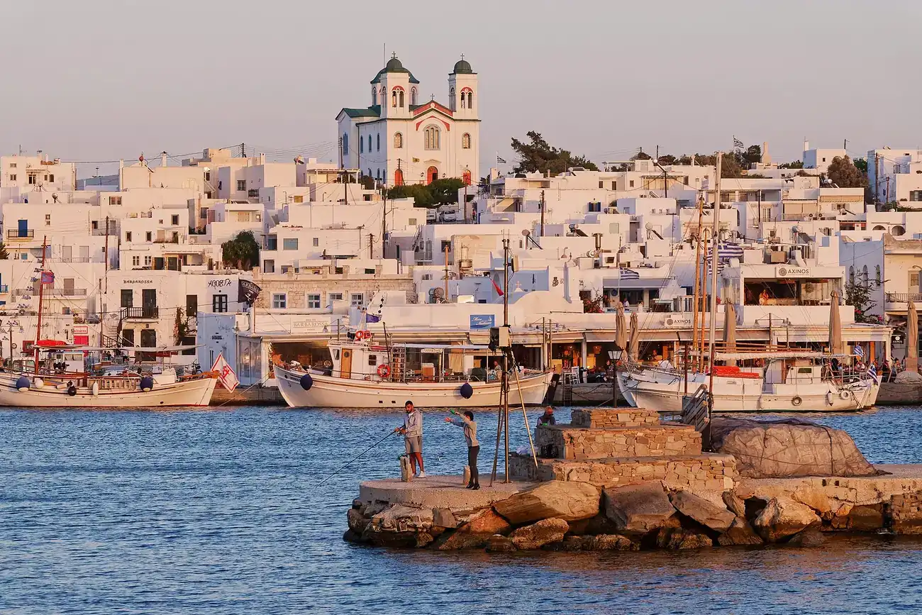 Puerto de Naoussa en Paros con barcas de pesca y el pueblo blanco al atardecer