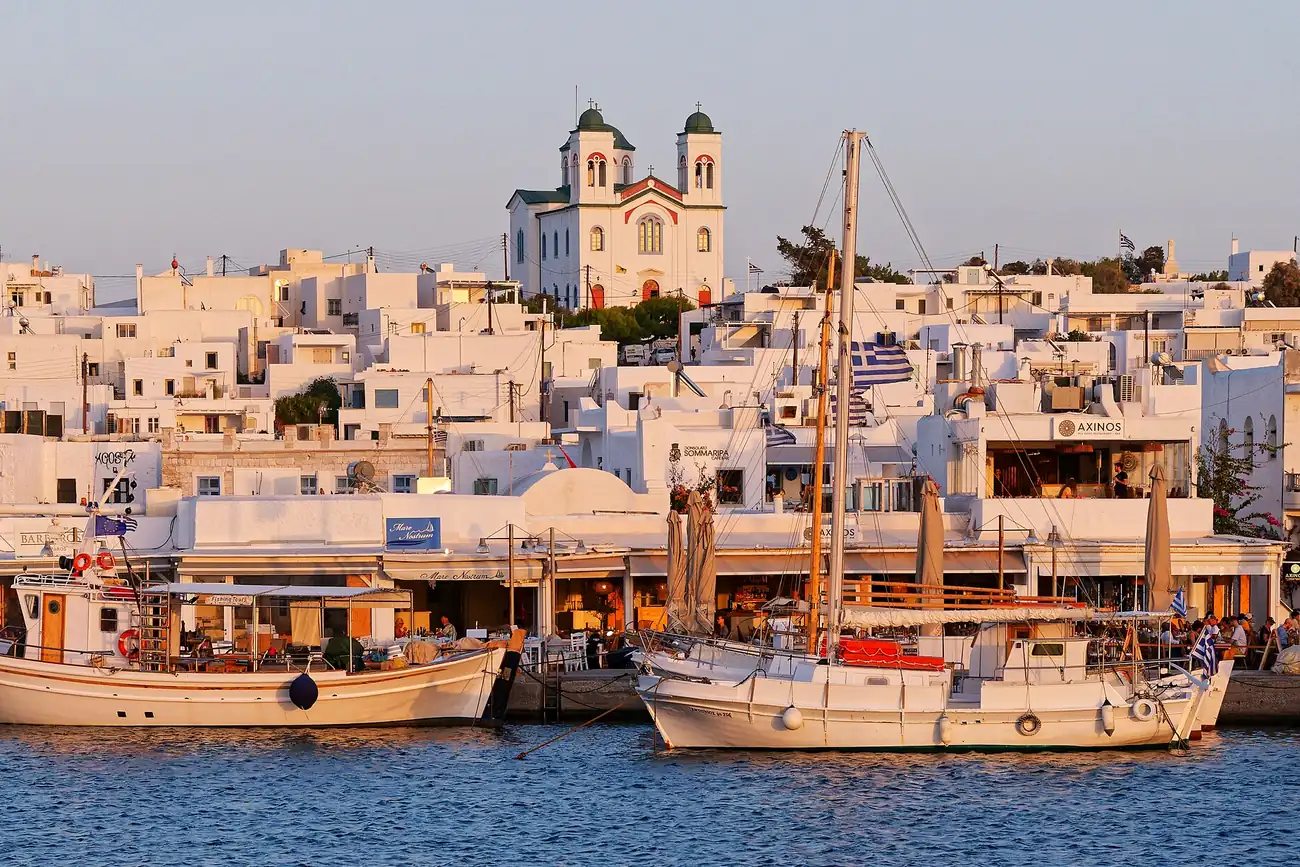 Veleros amarrados frente a las terrazas del puerto de Naoussa en Paros al atardecer