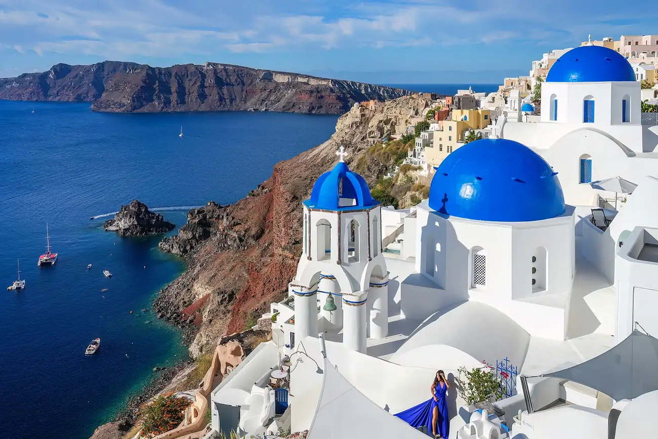 Las tres cúpulas azules de Oia sobre la caldera de Santorini, con el mar y la isla de Thirassia al fondo
