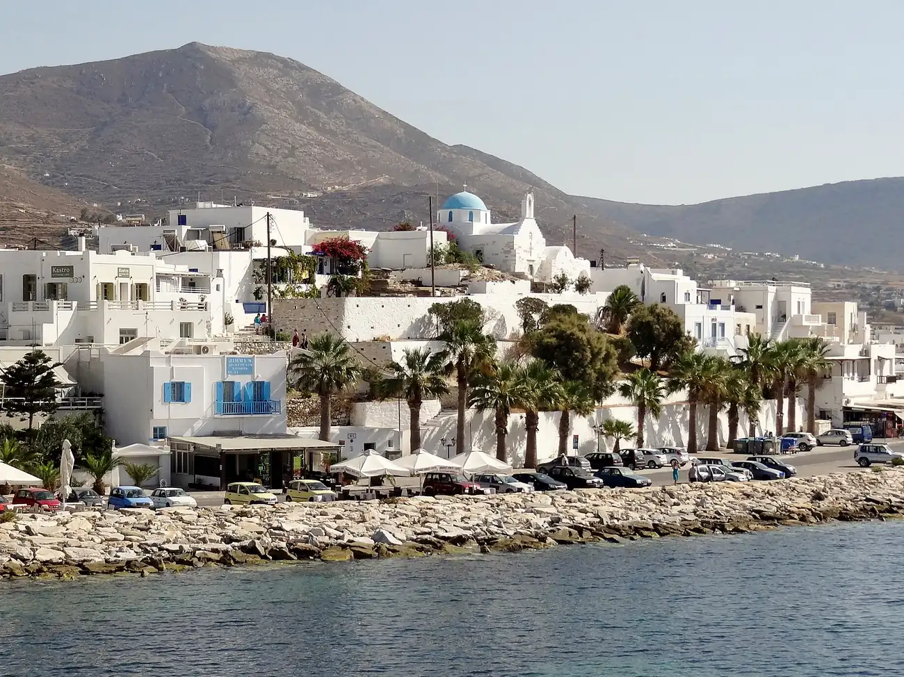 Paseo marítimo de Parikia, la capital de Paros, con palmeras y la montaña detrás